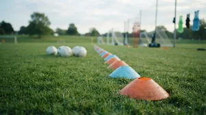 Trainingskegel, Netz und Sportbälle neben einem Fußballfeld